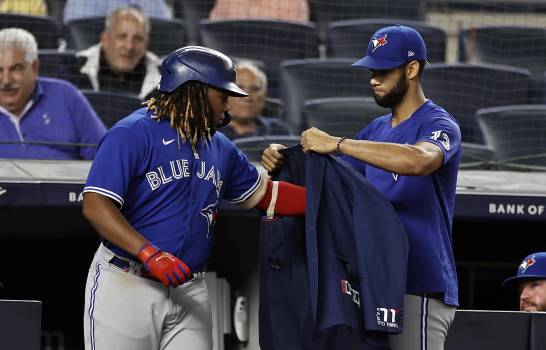 El cubano Lourdes Gurriel, de los Azulejos de Toronto, coloca la chaqueta de los jonrones al dominicano Vladimir Guerrero Jr., el miércoles 8 de septiembre de 2021, en un juego ante los Yanquis de Nueva York (AP/Adam Hunger)