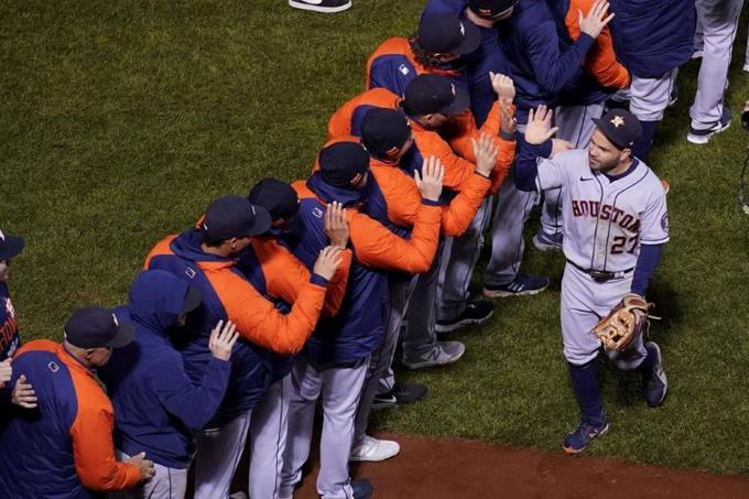 El venezolano José Altuve festeja con sus compañeros de los Astros de Houston tras vencer a los Medias Rojas de Boston en el cuarto juego de la Serie de Campeonato.
