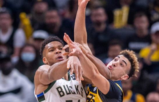 Giannis Antetokounmpo (34) pelea con un balón con el dominicano Chris Duarte en el encuentro del domingo 28 de noviembre del 2021. (AP PHOTO/DOUG MCSCHOOLER)