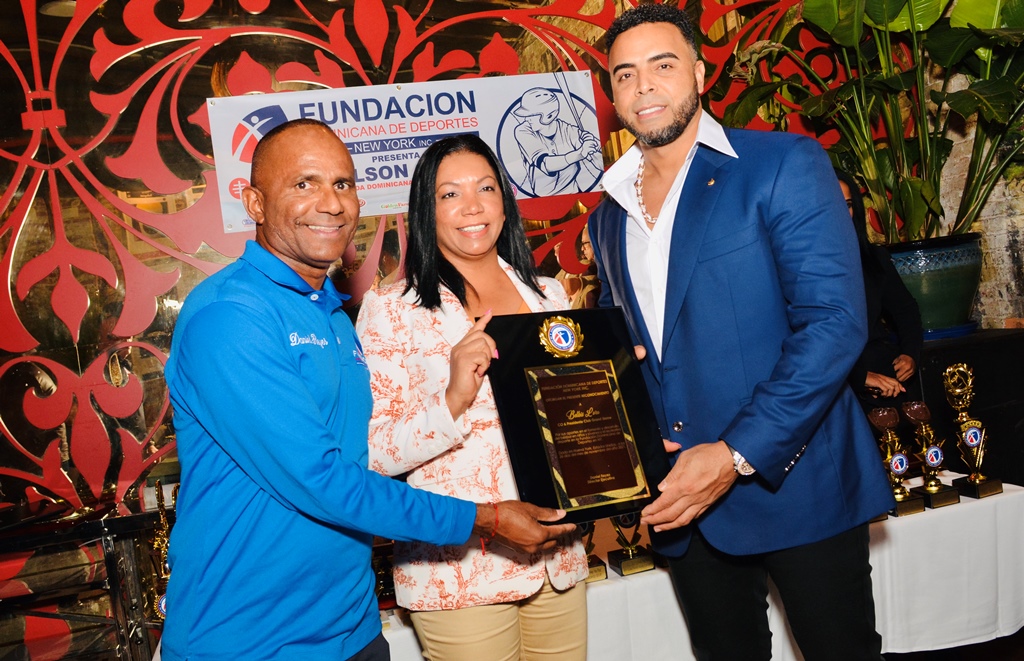 El destacado pelotero dominicano Nelson Cruz, (der.) y Daniel Reyes, (izq.), entregan el especial reconocimiento a Belkis Lora.