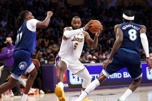 El alero de los Lakers de Los Ángeles LeBron James ataca el canasto ante la defensiva del pívot Naz Reid y del alero Jarred Vanderbilt, ambos de los Timberwolves de Minnesota, en la primera mitad del juego del domingo 2 de enero de 2022, en Los Ángeles. (AP Foto/Ringo H.W. Chiu) (The Associated Press)