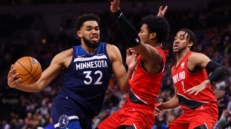 Karl-Anthony Towns, derecha, de los Timberwolves de Minnesota, busca rodear a Greg Brown III, de los Trail Blazers de Portland, para atacar la canasta, en el primer cuarto del juego de baloncesto de la NBA, el lunes 7 de marzo de 2022, en Minneápolis. (AP/BRUCE KLUCKHOHN)