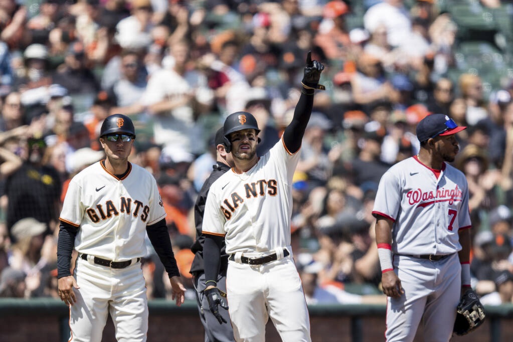 Luis González, centro de los Gigantes de San Francisco, hace un gesto frente al antesalista de los Nacionales de Washington, Maikel Franco (7), luego de avanzar a la tercera base durante la quinta entrada de un juego de béisbol en San Francisco, el sábado 30 de abril de 2022. (Foto AP/ /John Hefti)