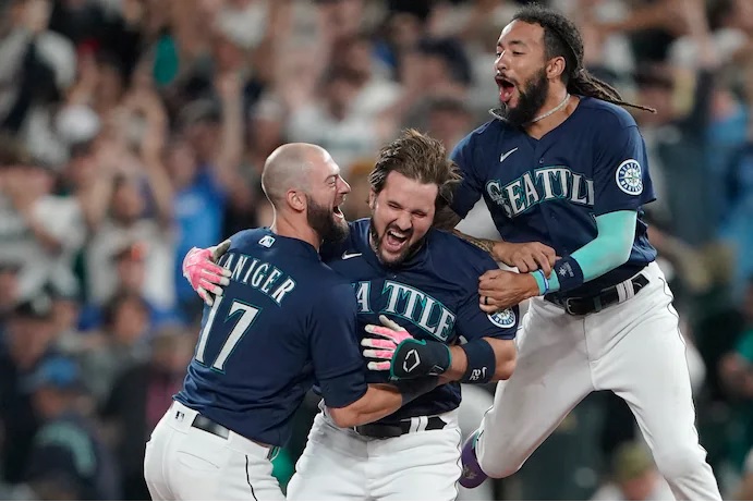 Seattle Mariners’ Luis Torrens, center, is greeted by teammates Mitch Haniger, left, and J.P. Crawford, right, after Torrens hit a walk-off RBI single to give the Mariners a 1-0 win over the New York Yankees in a 13-inning baseball game, Tuesday, Aug. 9, 2022, in Seattle. (AP Photo/Ted S. Warren)