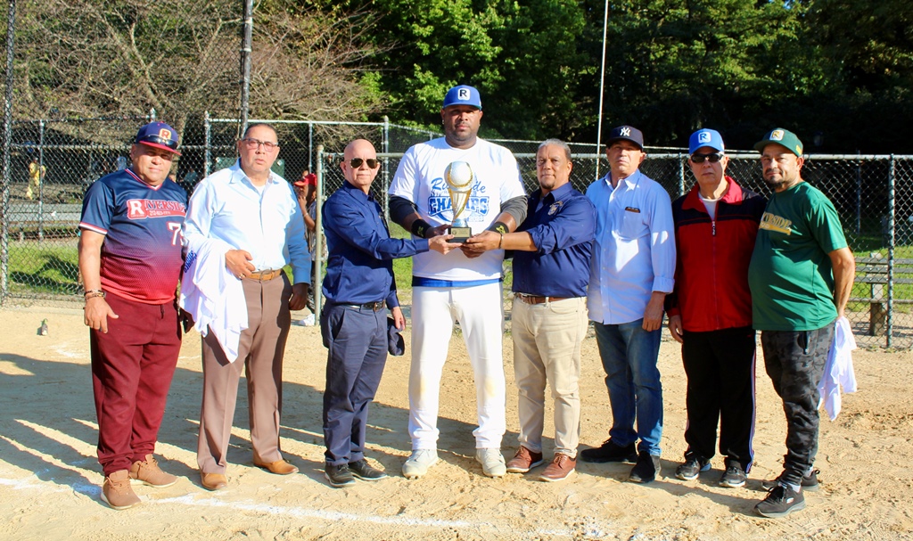 Persio Fernández, (37), presidente de Riverside Car Service, y Digno Hidalgo, (193), tesorero, encabezan la entrega del trofeo de campeón al manager Joel Brito.