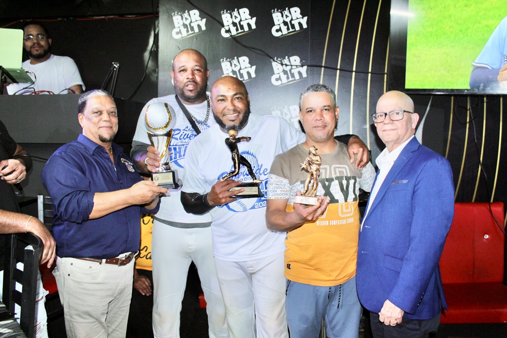 Persio Fernández, (37), presidente de Riverside Car Service, (Der.) y Digno Hidalgo, (Izq.), (193), tesorero, premian a Joel Brito, copa de campeón; Jeury Soriano, MVP y a Alberto Gómez, lanzador destacado.