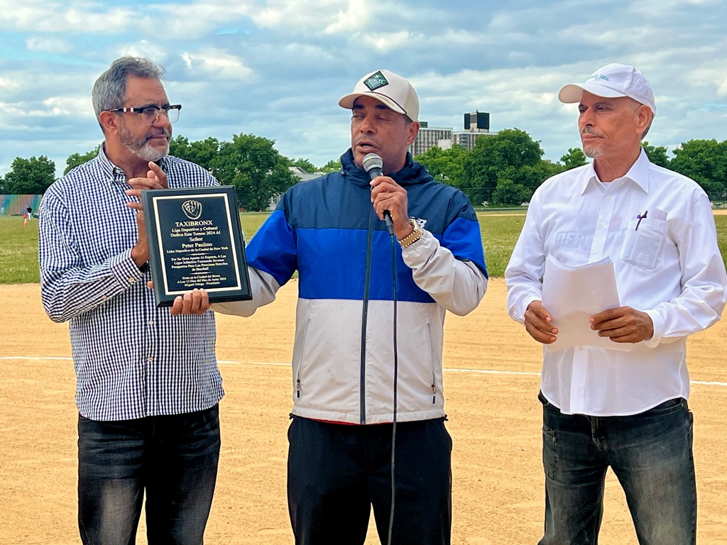 Miguel Ortega, en presencia de Amado López, entrega una placa de reconocimiento a Peter Paulino, quien agradece el gesto.