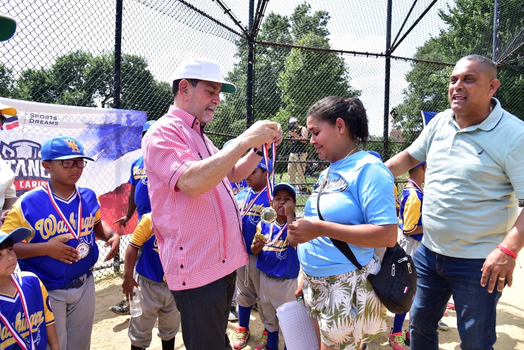 Eligio Jáquez, captado colocando una medalla en uno de los eventos comunitarios, observa Roberto Rojas, líder deportista y comunitario.