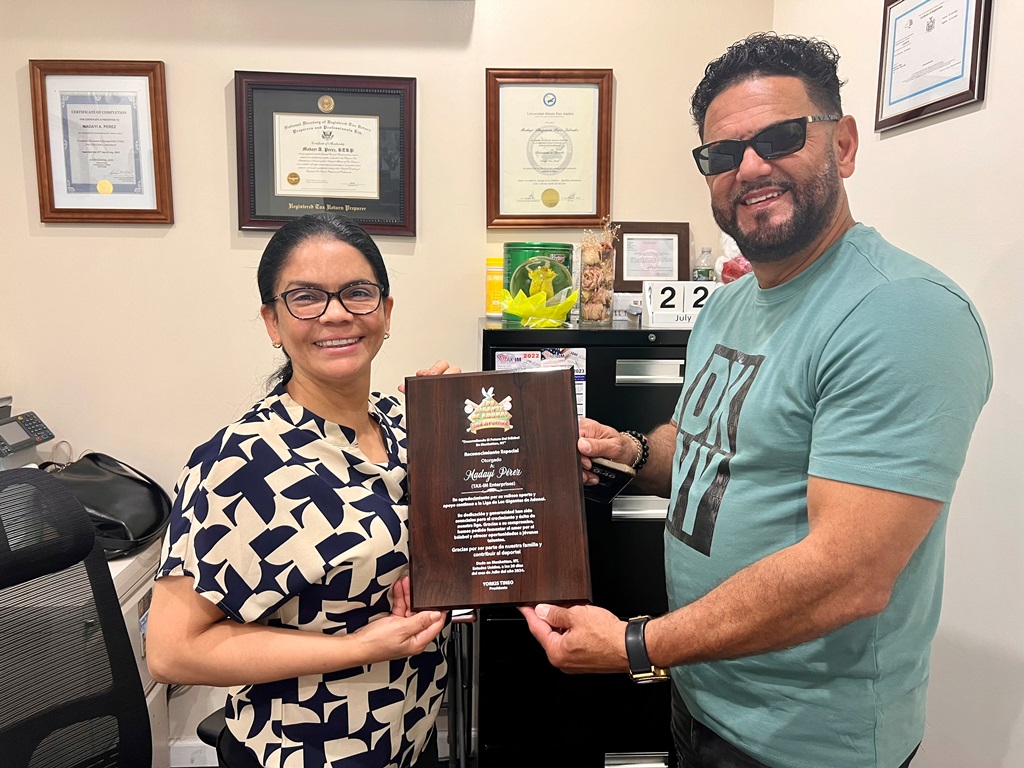 Yorki Tineo, (der.), entrega placa de reconocimiento a Madayi Pérez, de TAX-IM Enterprises.