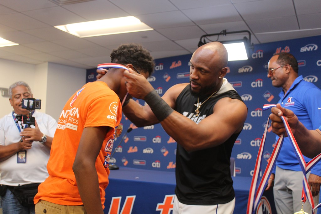Starling Marte, guardabosque derecho de los Mets, premia con la medalla de campeón a uno de los atletas de la división 11-12 años.