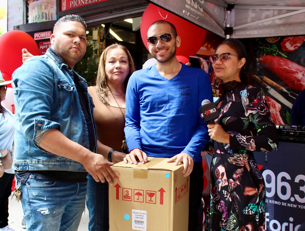 Aníbal Tejada, manager general de Pionner Supermarket, Rosa Paulino y Honey Mejía, entregan una nevera a uno de los agraciados.