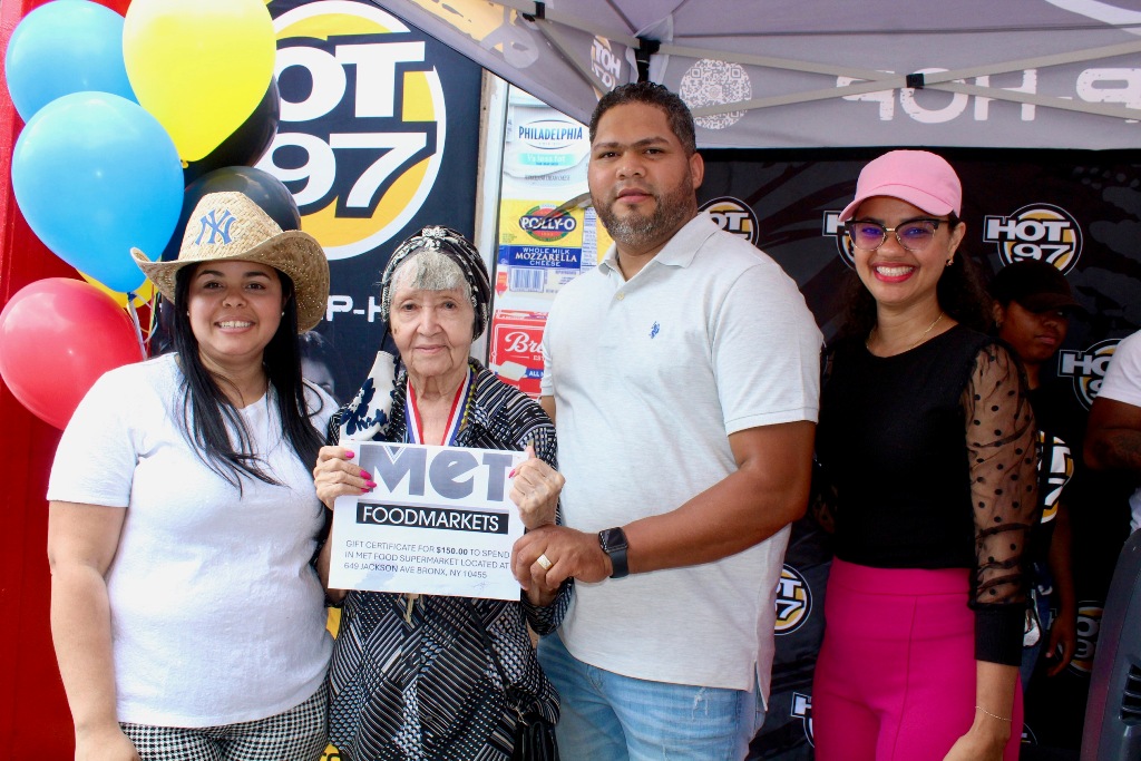 Aníbal Tejada y Marleny Gómez Medina, entregan a la doña un certificado equivalente a 150 dólares para comprar en Met FoodMarkerts.