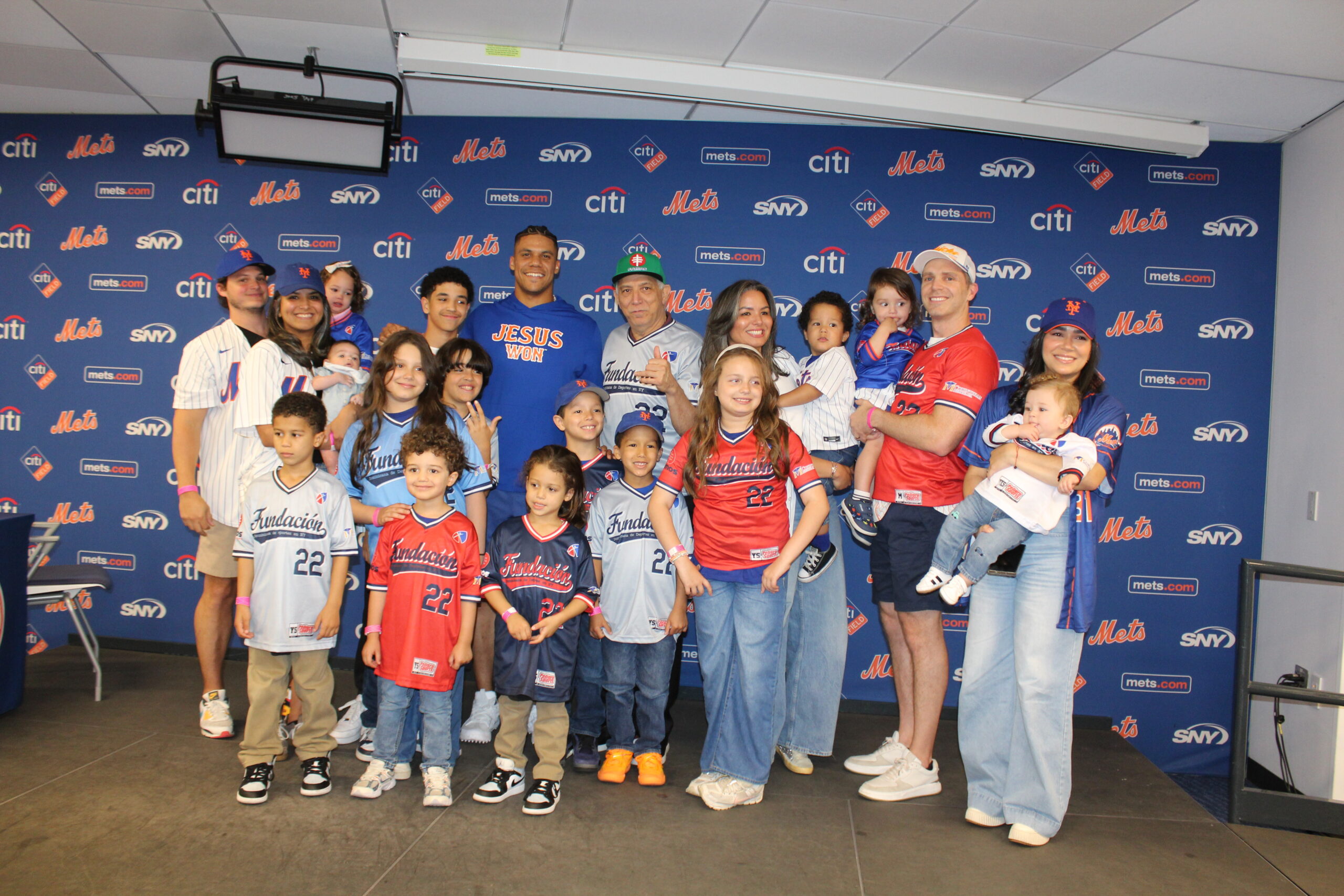 Integrantes de las familias Tallaj, De los Santos Tallaj, Tsouklidis Tallaj, Tallaj de los Ángeles, Carilli Tallaj y Castillo Rancier posan junto a la estrella de los Mets de Nueva York, Juan Soto, durante la celebración del primer cumpleaños de Theodore Carilli en Citi Field.