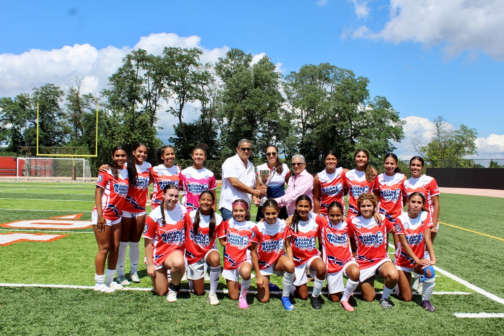 Roberto Rojas y José Ortiz entregan la copa de campeonas de la categoría Sub-17 a la dirigente del onceno de New Jersey, tras conquistar el título en los II Juegos Deportivos Juan Pablo Duarte.